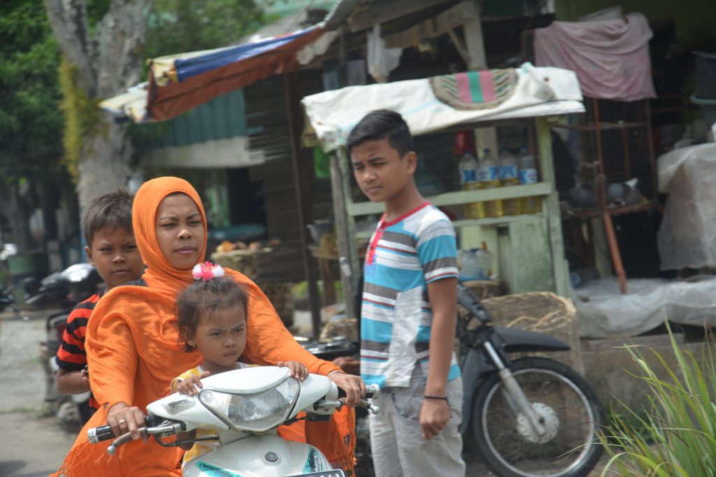 Muslim woman riding motorcycle on streets in Medan, Indonesia