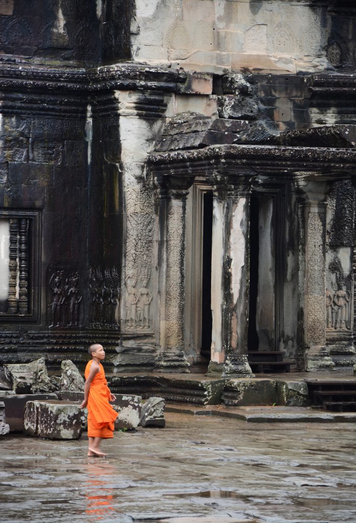 monk strolling through Angkor Wat temple, Cambodia