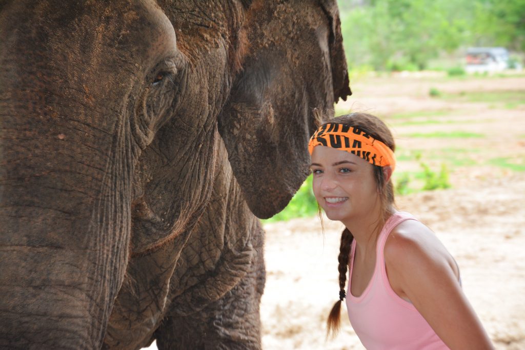 Girl smiles with elephant next to her