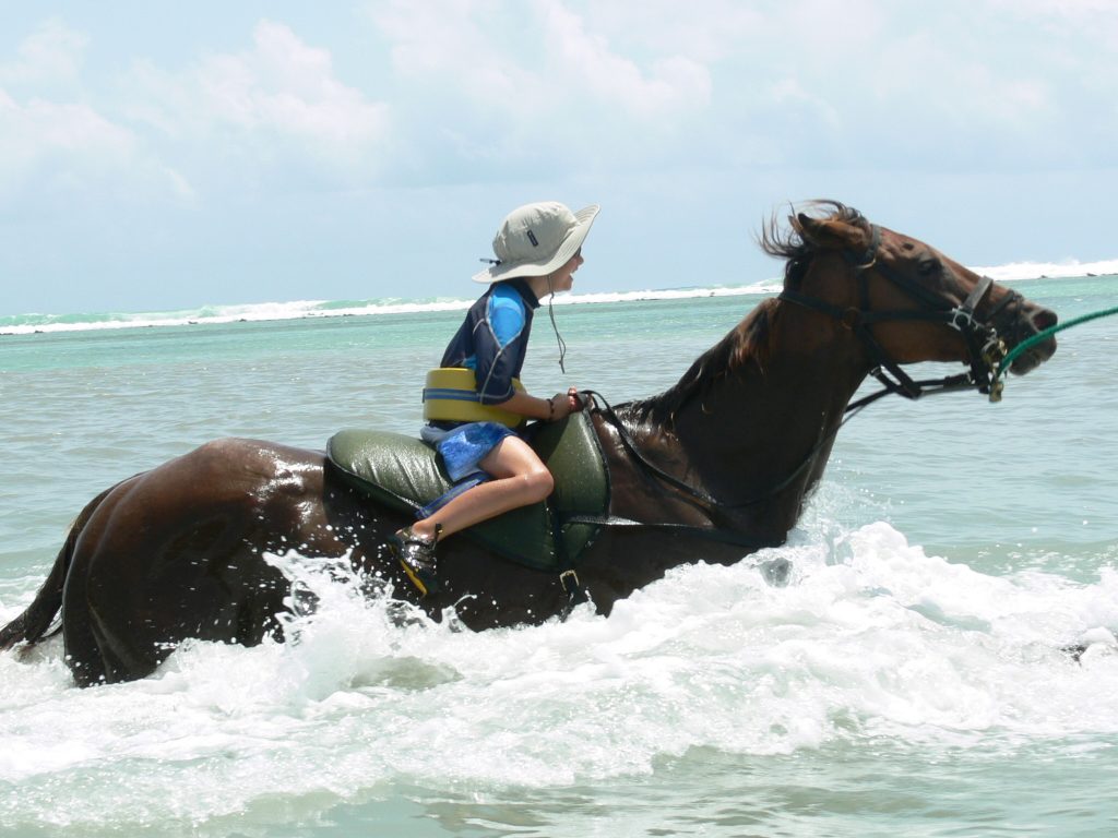 Boy on horse in ocean in Jamaica