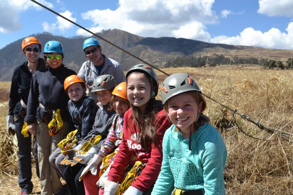 Group of kids and adults with helmets on ready to zip line in Peru