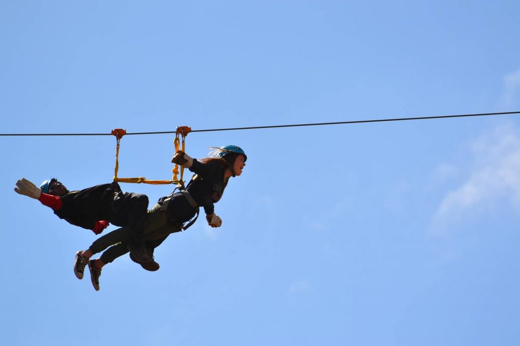 Girl on zip line in "bird" pose