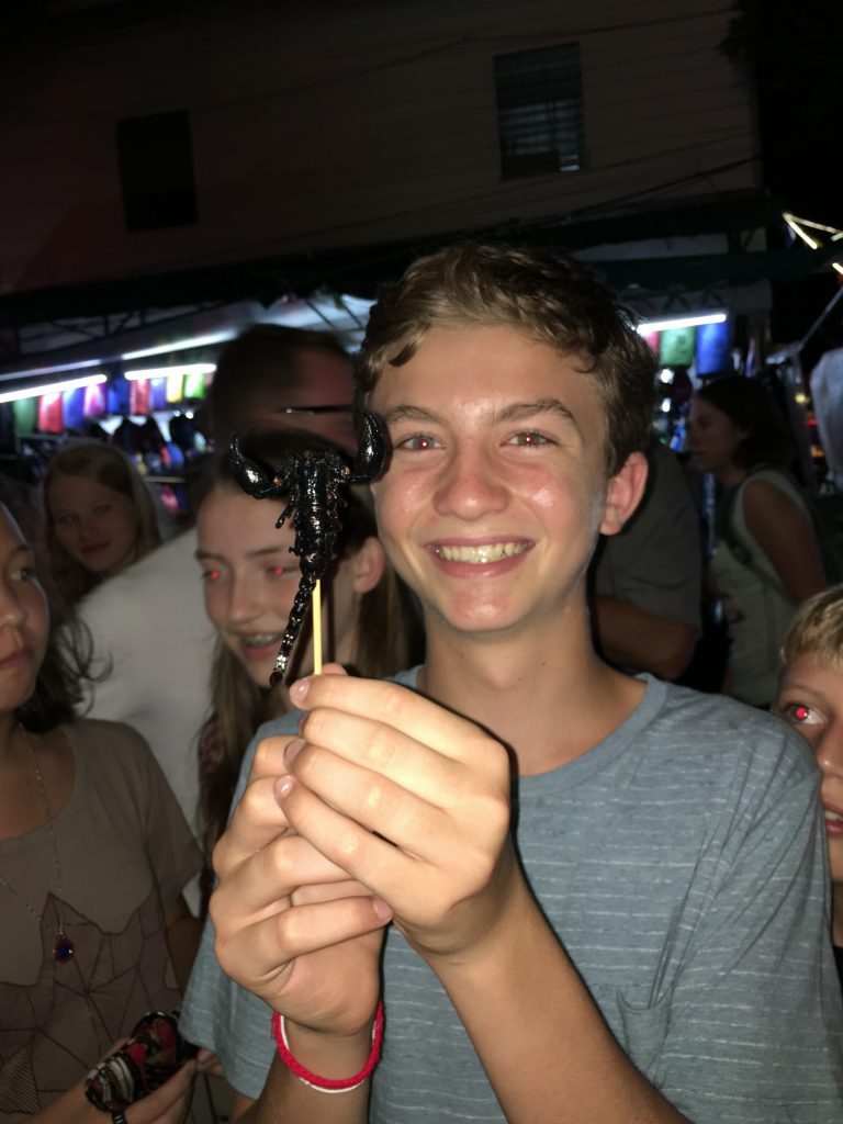 Boy with scorpion on stick in Thailand