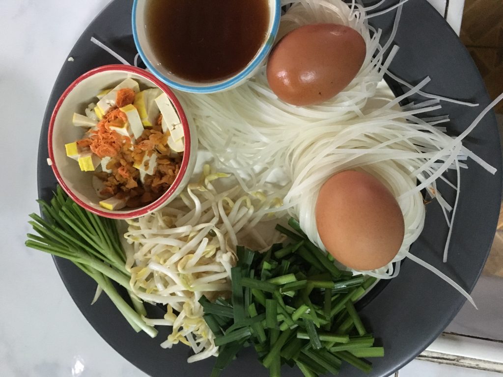 Pad Thai ingredients including noodles, eggs, sprouts, tofu and green onions on a plate at cooking school in Thailand