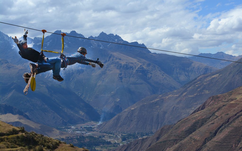 Boy zip lining in superman pose above Sacred Valley, Peru