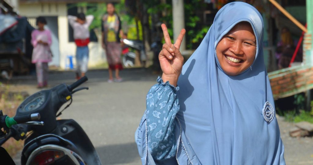 Lady in traditional Muslim dress showing peace sign