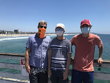 Father and two sons with ocean and beach in background