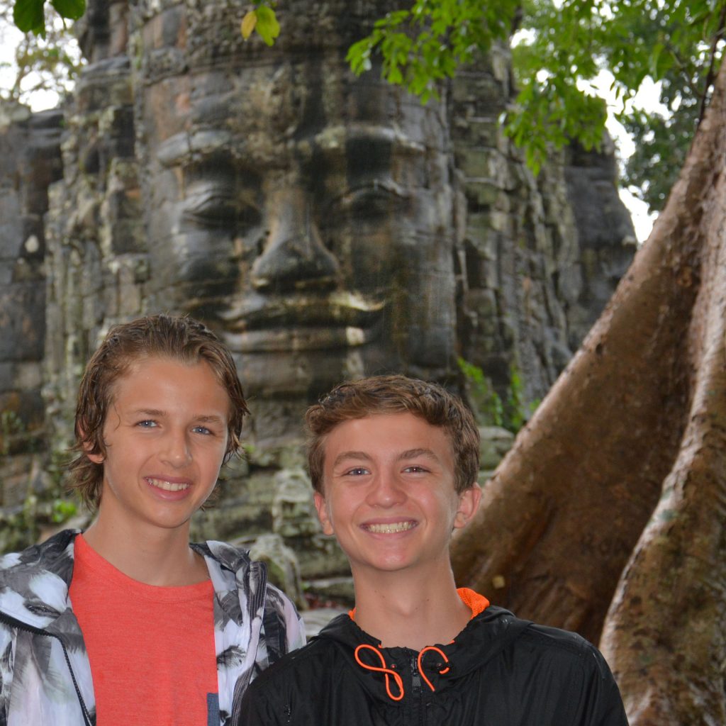 boys posing in front of carved face at Angkor Wat