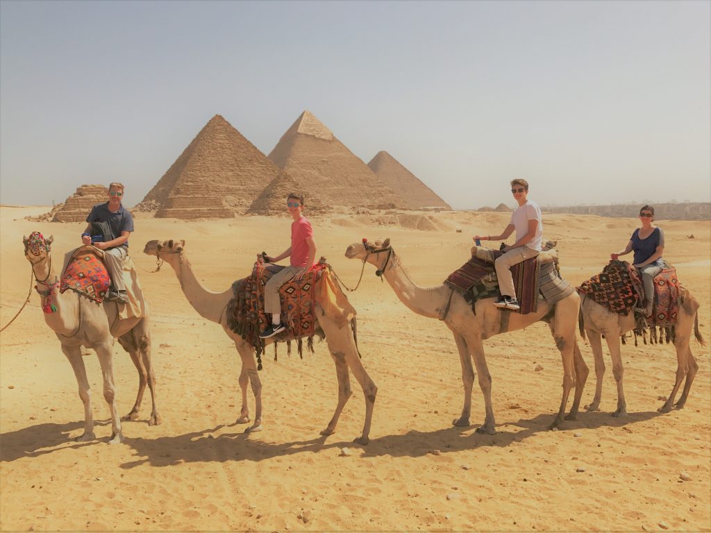 family on camels with Great Pyramids of Giza in background