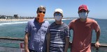 Father and two sons with ocean and beach in background